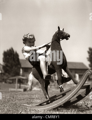 1930s Little Boy fuori a giocare a cavallo sul giocattolo CAVALLO A DONDOLO Foto Stock