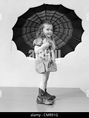 1930s 1940s bambino sorridente bambina azienda giornata piovosa ombrello Foto Stock