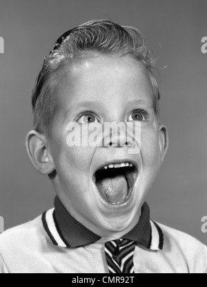 Anni sessanta ritratto ragazzo eccitato con la bocca aperta a ridere Foto Stock