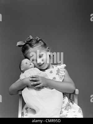 1940s bambino poco sorridente ragazza bionda tenendo la bambola seduto in poltrona Foto Stock