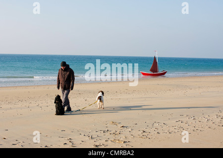 Uomo e 2 cani su una soleggiata giornata invernale in spiaggia in Normandia, Francia. Modello di rilascio. Foto Stock