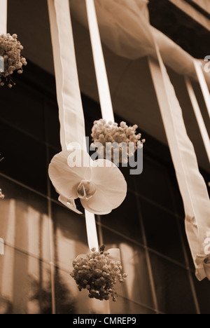 Appendere bianco fiori matrimonio sulla porta anteriore di una chiesa, tonalità seppia Foto Stock