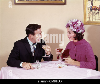 Anni sessanta giovane bevendo un cocktail al tavolo al marito e moglie indoor Foto Stock