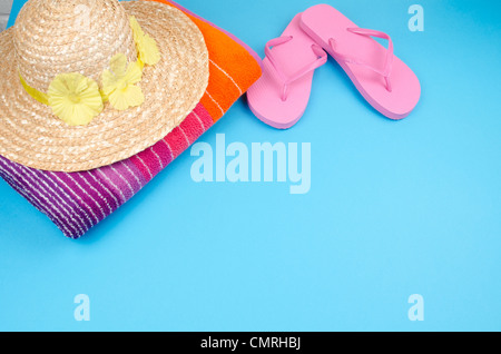 Rosa flip-flop su uno sfondo blu con un cappello per il sole e telo da spiaggia Foto Stock