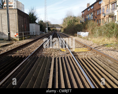 La vista tra due elettrico ferroviario di brani da un passaggio a livello Foto Stock