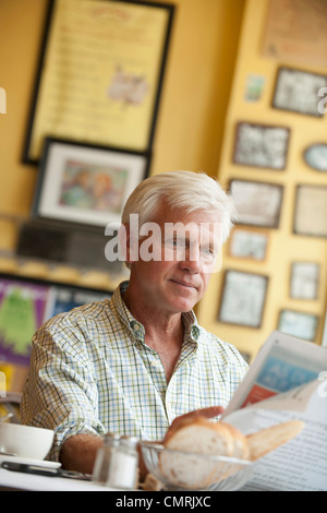 Uomo caucasico leggendo il giornale in ristorante Foto Stock