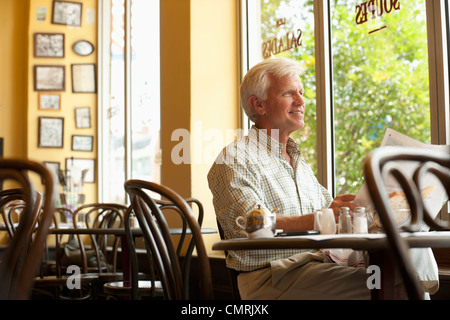 Uomo caucasico leggendo il giornale in ristorante Foto Stock