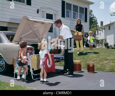 Madre di famiglia padre tre figlie Imballaggio bagagli in auto per vacanza OUTDOOR 1970s Foto Stock