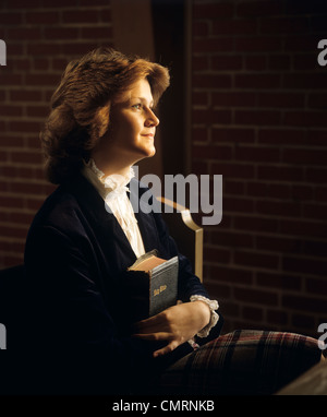 Negli anni ottanta la luce morbida ritratto di profilo di sorridere GIOVANE DONNA HOLDING e abbracciando LA SUA BIBBIA Foto Stock