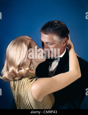 Coppia romantica che abbraccia circa al bacio tra marito e moglie ABITO DA SERA STUDIO degli anni settanta Foto Stock