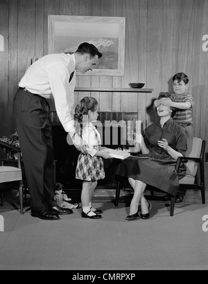 Degli anni Cinquanta la famiglia SOGGIORNO DONNA MADRE GETTING regalo a sorpresa da bambini Figlia Figlio marito Foto Stock