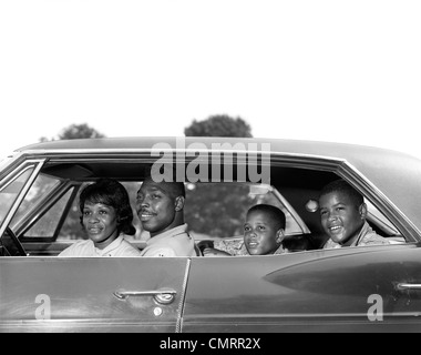 Anni sessanta VISTA LATERALE OUTDOOR sorridente afro-americano della famiglia padre MADRE DI DUE FIGLI IN SEDUTA Sedan quattro porte AUTOMOBILE Foto Stock