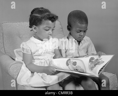 Anni sessanta AFRICAN-AMERICAN BOY E LETTURA DELLA RAGAZZA PRENOTA SEDUTA Foto Stock
