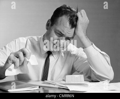 Anni sessanta frustrato imprenditore MANO A FRONTE SGUALCIMENTO CARTA IN MANO Foto Stock