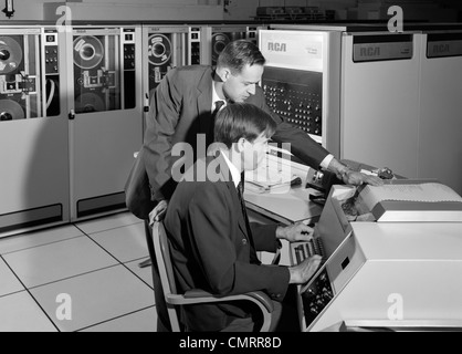 Anni sessanta due proprietari la programmazione di grandi Mainframe Computer circondato da dati unità nastro di archiviazione interna per ufficio Foto Stock