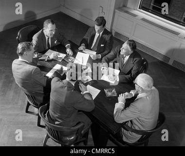 Anni Cinquanta anni sessanta sei imprenditori dirigenti responsabili dei venditori di meeting aziendali intorno a un tavolo per conferenza Foto Stock