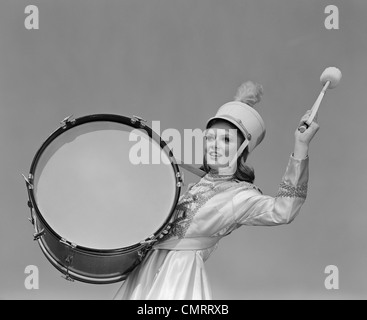 Anni sessanta sorridente giovane donna banda portante uniforme Riproduzione di grande tamburo Foto Stock