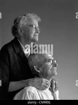 Anni sessanta ritratto della coppia di anziani nel loro 80s usurata dal tempo mani toccano STUDIO Foto Stock