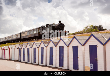 Regno Unito, Inghilterra, Devon, Torquay, Goodrington Sands, Dartmouth a Paignton treno a vapore che passa sopra la spiaggia di capanne Foto Stock