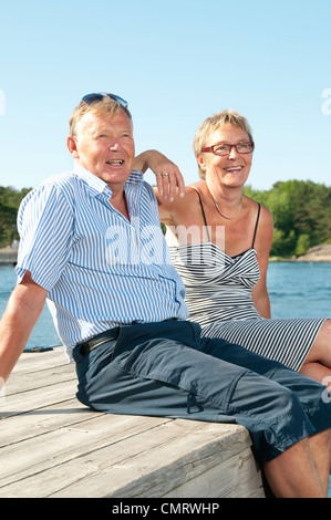 Due persone sedute sul molo dall'acqua Foto Stock