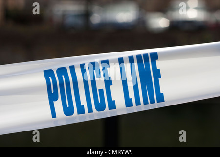 Nastro di polizia per la scena del crimine, la scrittura è "linea di polizia" in blu su bianco, offuscata dettaglio in sfondo mostrante la posizione generica. Foto Stock