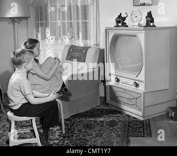 Degli anni cinquanta un ragazzo e una ragazza a guardare la TV IN SOGGIORNO Foto Stock