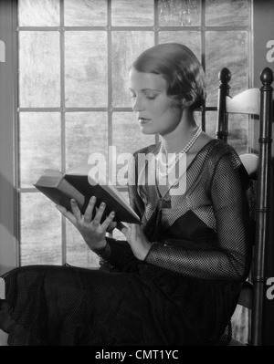 1920s 1930 eleganti donna che indossa perle seduta dalla finestra Rubrica di lettura Foto Stock