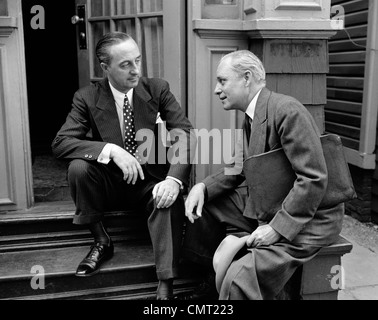 1930s 1940s venditore e proprietario di casa Uomo seduto insieme sulla parte anteriore STOOP parlando la presentazione di vendita Foto Stock