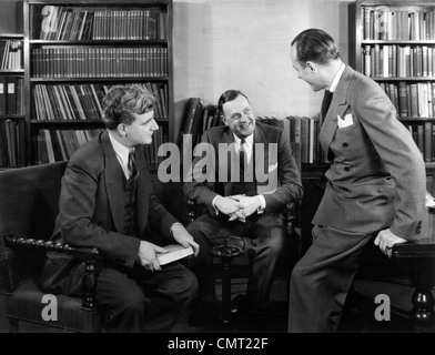 1940s GRUPPO DI TRE UOMINI DI AFFARI seduti insieme in biblioteca parlando sorridente Foto Stock