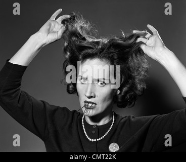 Anni sessanta donna con capelli BRUTTA GIORNATA TENENDO I PERNI DEI CAPELLI IN BOCCA frustrato Foto Stock