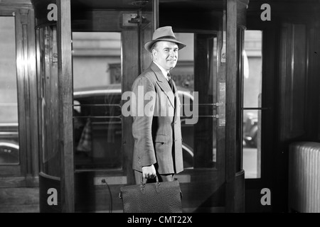 1930s 1940 imprenditore sorridente IN HAT doppio petto tuta valigetta lasciando edificio attraverso la porta girevole guardando la fotocamera Foto Stock