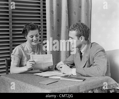 1930s giovane uomo donna seduta a tavola andando su paper Foto Stock