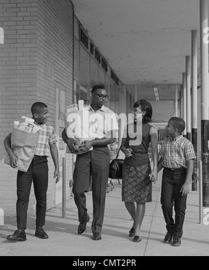 Anni sessanta famiglia americana africana che trasportano sacchi di negozi di generi alimentari Foto Stock