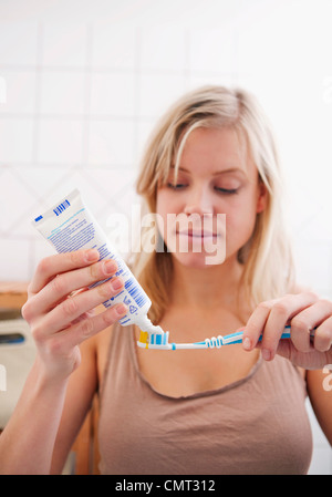 Donna mettendo il dentifricio su uno spazzolino da denti Foto Stock