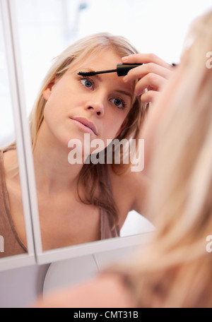 Donna in piedi nel bagno di mettere sul make-up Foto Stock