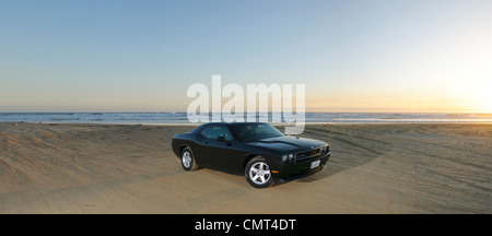 Retrò auto sulla spiaggia sabbiosa in California negli Stati Uniti al tramonto con il mare e l'orizzonte Foto Stock