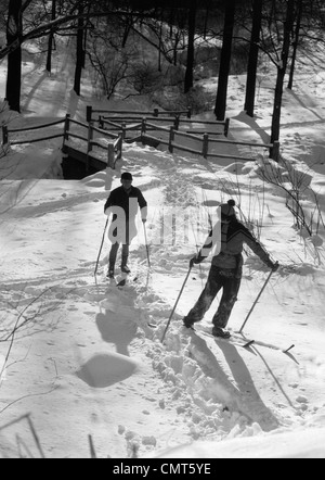 1930s GIOVANE UOMO E DONNA SCI CROSS COUNTRY nel bosco invernale sulla neve all'aperto Foto Stock