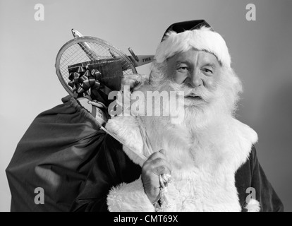 Anni sessanta ritratto sorridente di Babbo Natale con il sacco di giocattoli di Natale presenta espulso sulla sua spalla Foto Stock