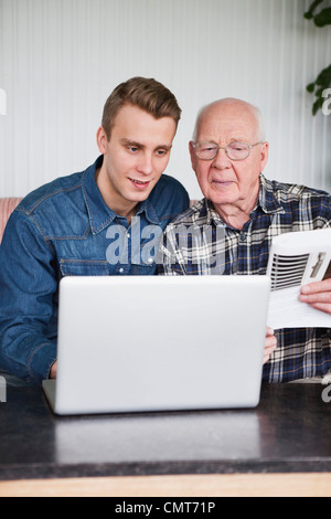 Giovane uomo insegnamento suo nonno su computer Foto Stock