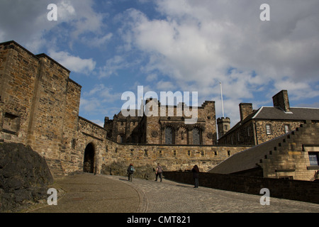 I turisti in una leggermente inclinata verso l'alto percorso interno al Castello di Edimburgo in Scozia, con edifici tutti intorno a loro. Foto Stock