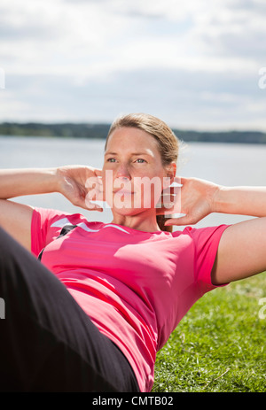 Donna facendo sit ups in posizione di parcheggio Foto Stock
