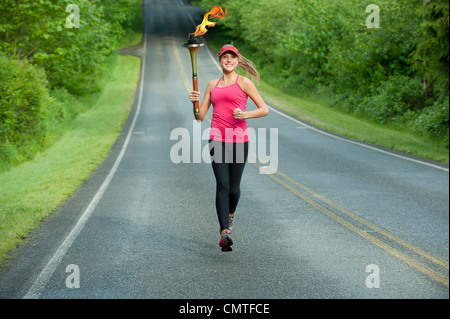 Caucasian atleta che corre con la fiaccola olimpica su strada in remoto Foto Stock