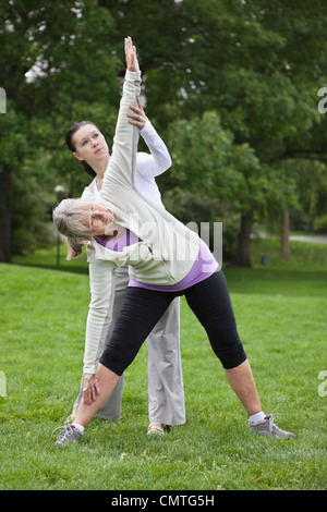 Trainer ad aiutare la donna a esercitare presso il park Foto Stock