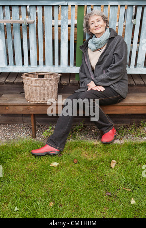 Ritratto di senior donna seduta su un banco di lavoro guardando la fotocamera Foto Stock
