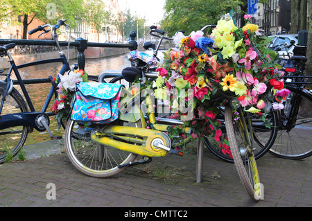 Le biciclette parcheggiate sulla sponda di un canale di Amsterdam, Olanda. Foto Stock