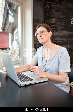 Donna che utilizza portatile a casa Foto Stock