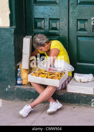 Una mezza età cubano femmina venditore ambulante si prepara per il suo giorno di vendita di dolci per le strade di l'Avana, Cuba. Foto Stock