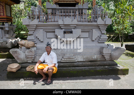 Un locale adoratore Balinese si siede vicino a un santuario al Tirtal Empul Temple, Bali, Indonesia Foto Stock