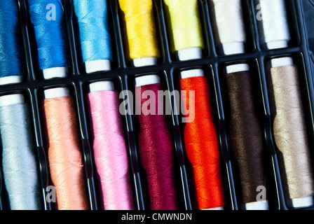 Multi-colore di bobine di cotone fotografato in corrispondenza di un angolo in Rosa blu marrone rossiccio peach giallo arancio e bianco Foto Stock