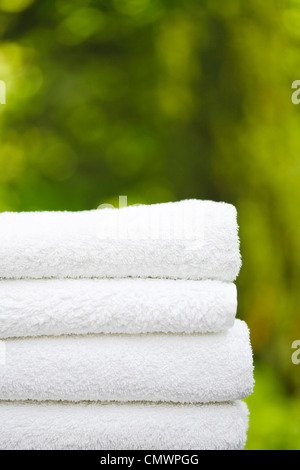 Pila di freschi asciugamani bianchi in un giardino con copyspace, ideale per raffigurante una day spa e wellness Foto Stock